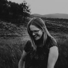 black and white photo of woman in field with mountains in the background