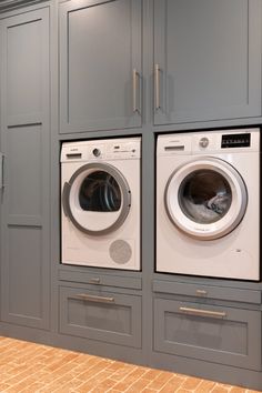 a washer and dryer in a laundry room with gray cupboards on the wall