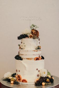 a three tiered cake with fruit and flowers on top