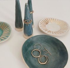 there are three vases and two plates with rings on them next to each other