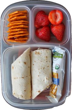 a lunch box with strawberries, crackers, and tortilla wrap in it