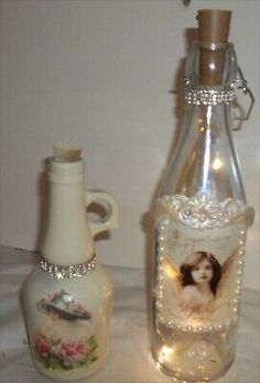 a glass bottle with an angel on it next to a ceramic vase and candle holder