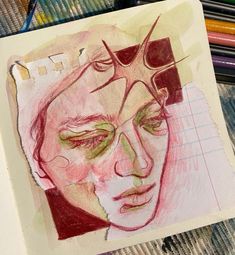 a drawing of a man's face with colored pencils on the table next to it