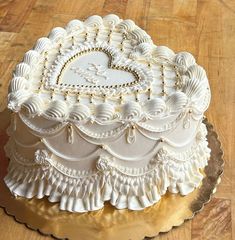 a wedding cake with white frosting and ruffles on top is sitting on a wooden table