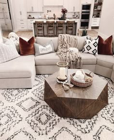 a living room filled with lots of furniture and pillows on top of a white rug