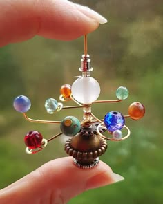 a hand holding a small metal object with many different colored beads on it's side