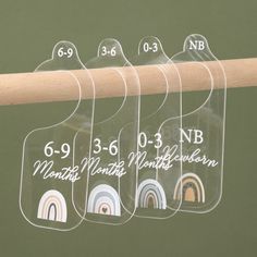 four clear acrylic tags with numbers on them hanging from a wooden stick in front of a green wall