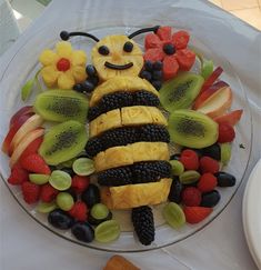 a cake made to look like a bee surrounded by fruits and vegetables on a plate