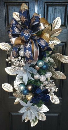 a blue and gold christmas wreath hanging on a black door with silver, gold and white decorations