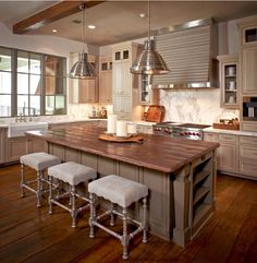 a kitchen with an island and stools in the center, surrounded by wooden flooring