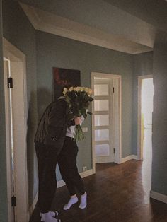 two people are walking in the hallway with flowers on their head and one person is holding a bouquet of flowers