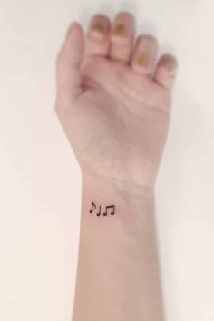 a woman's wrist with a small tattoo on it that says music in black ink