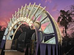 a large metal gate with lights on it's sides in front of a purple sky