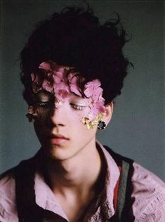 a man with flowers in his hair is looking at the camera while wearing an eye patch