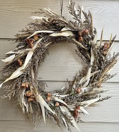 a dried wreath is hanging on the side of a building with pine cones and dry grass