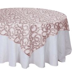 a round table with a pink and white tablecloth on top of it that has an intricate design