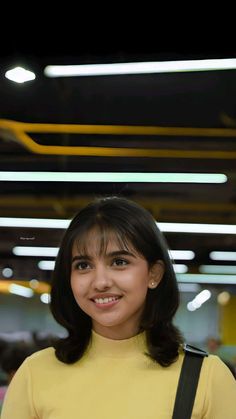 a woman in a yellow shirt is smiling at the camera with her hand on her hip