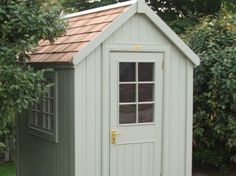 a small shed with a door and window on the side, in front of some trees