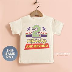 a white t - shirt with the words 2nd birthday and beyond on it hanging from a wooden hanger