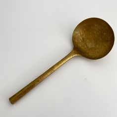 an antique brass spoon on a white background