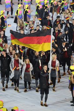 a large group of people walking down a street holding flags and wearing black, red, yellow and green