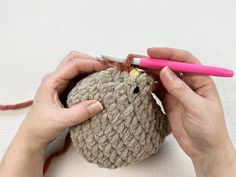 a woman is crocheting a small stuffed animal with a pink pen in her hand