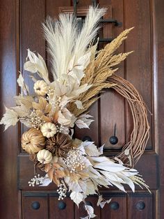 a wreath with dried flowers and leaves hanging on the front door to decorate it for fall