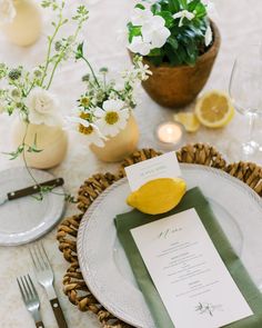 the table is set with plates, silverware and lemons