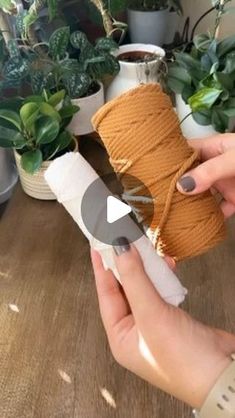 a person is holding a spool of twine in front of some potted plants