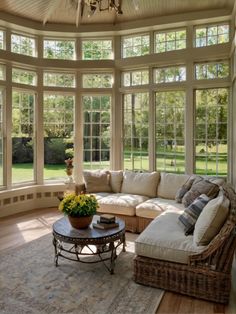 a sun room with couches, tables and windows on the ceiling is lit by a chandelier