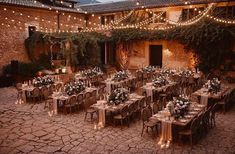 an outdoor dining area with tables, chairs and string lights strung over the building's courtyard