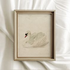 a white swan sitting on top of a bed next to a white sheet covered wall