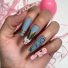 a woman's hand with blue, pink and gold nail polishes on it