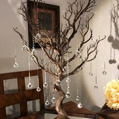 a tree with ornaments hanging from it's branches in front of a mirror on a table