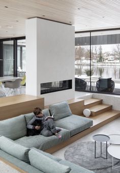 a person sitting on a couch in a living room next to a table and stairs