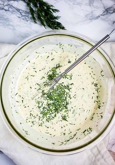 a glass bowl filled with cream and herbs