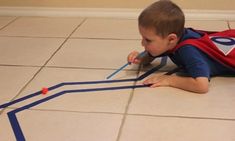 a young boy laying on the floor playing with construction paper