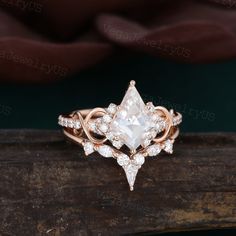 a white diamond ring sitting on top of a piece of wood