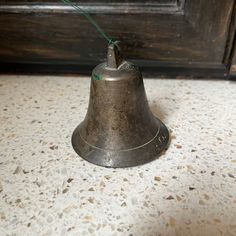 a metal bell with a green string attached to it