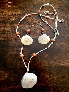 a necklace with two seashells hanging from it's sides on a wooden table