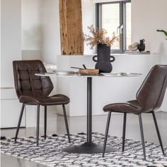 two brown chairs sitting at a small table