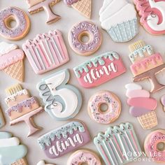 some decorated cookies are laying on a white table top with pink and blue icing