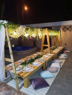 a table set up with plates and place settings for an outdoor dinner or party at night