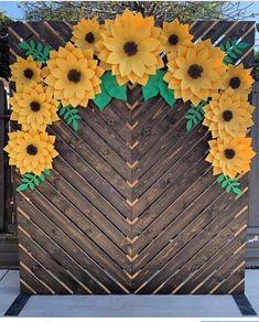 a wooden fence decorated with yellow flowers and green leaves in the shape of a heart