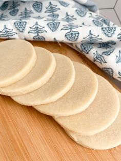 a stack of flat bread on top of a wooden cutting board next to a blue and white towel