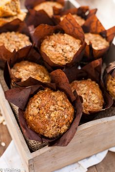 some muffins are sitting in a wooden box on a table with napkins