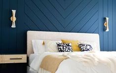 a bedroom with blue walls and white bedding, yellow throw pillows on the headboard