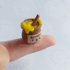 a tiny toy is sitting on top of a persons finger that has honey in it