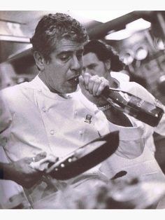 a man holding a bottle in his right hand while standing next to another man wearing a chef's uniform