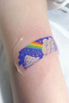 a person's arm with a rainbow on it and clouds painted on the side